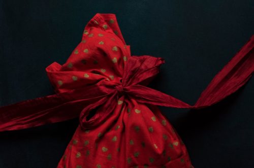red and gold polka-dot drawstring pack on black surface